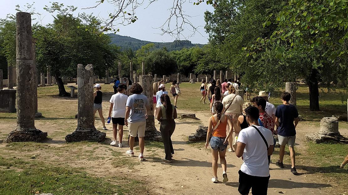 Students walk among the ruins of ancient Olympia on a guided tour.